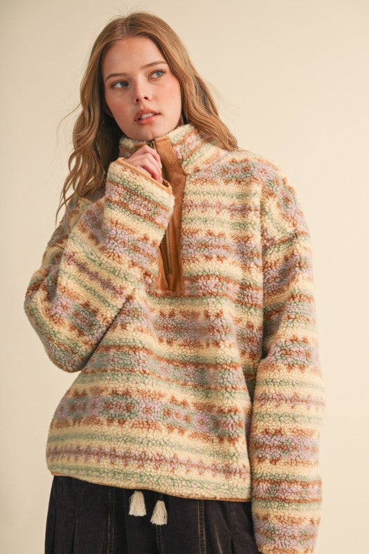 A woman wearing a fuzzy striped knit sweater with a brown tassel tie at the collar, photographed against a plain beige studio background.